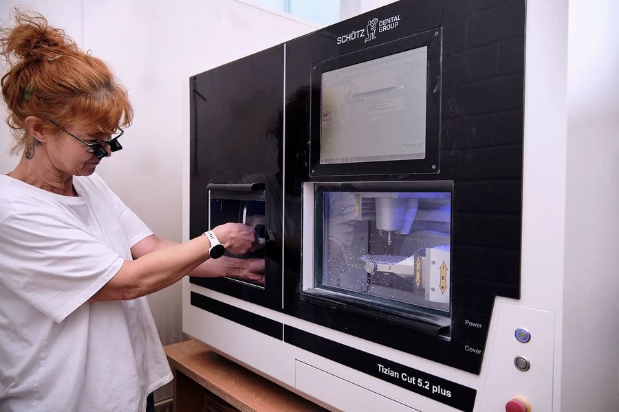 Mitarbeiterin mit Lupenbrille an einer Fräsmaschine