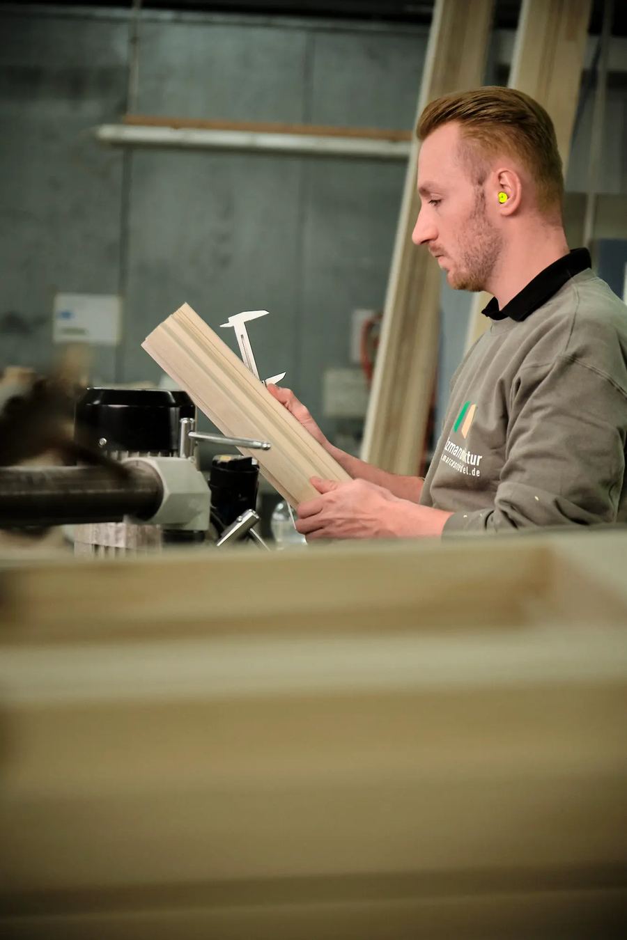Mitarbeiter mit einem Holzteil in der Schreinerei