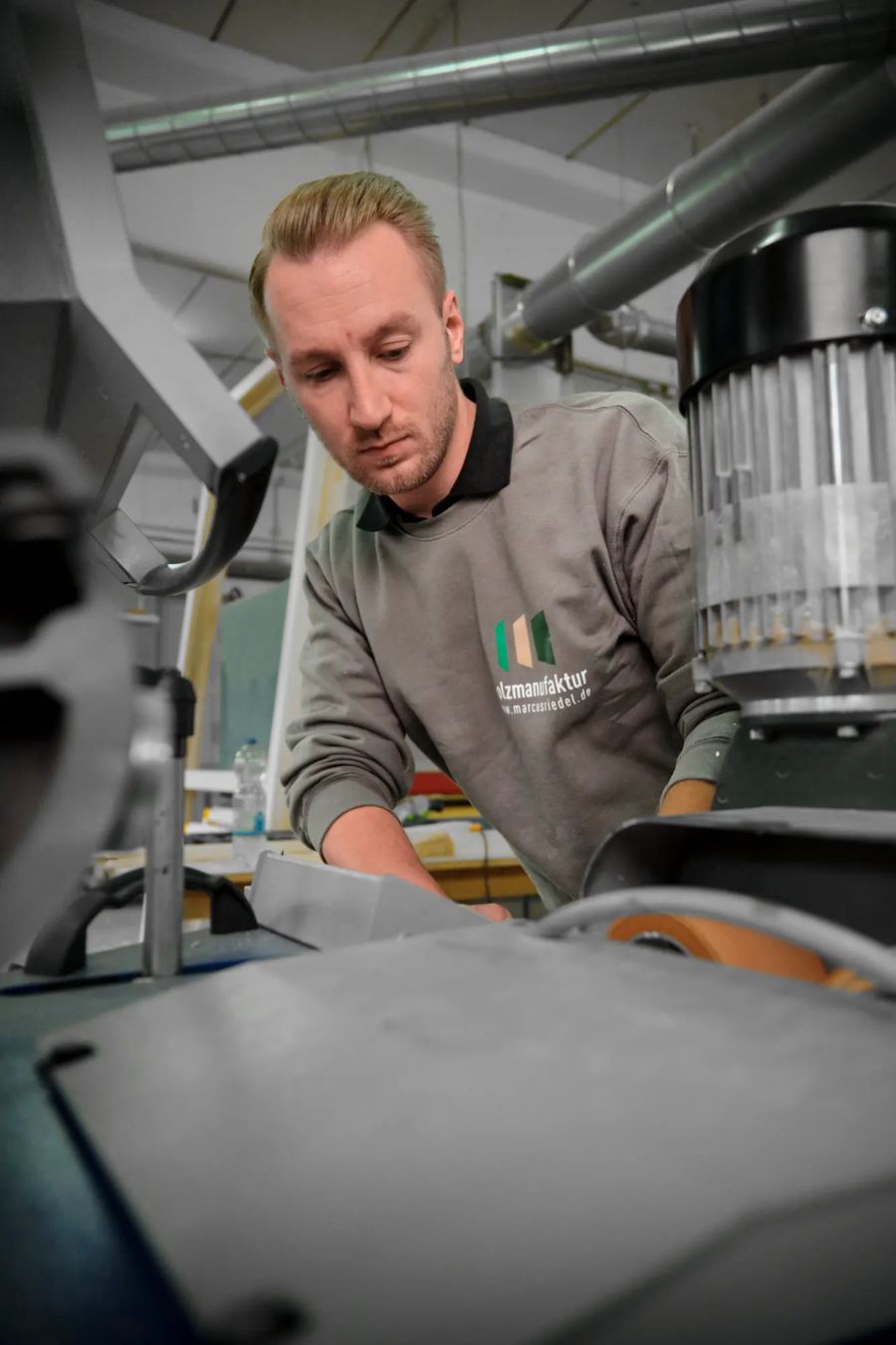 Mitarbeiter beugt sich in der Werkstatt über eine Maschine